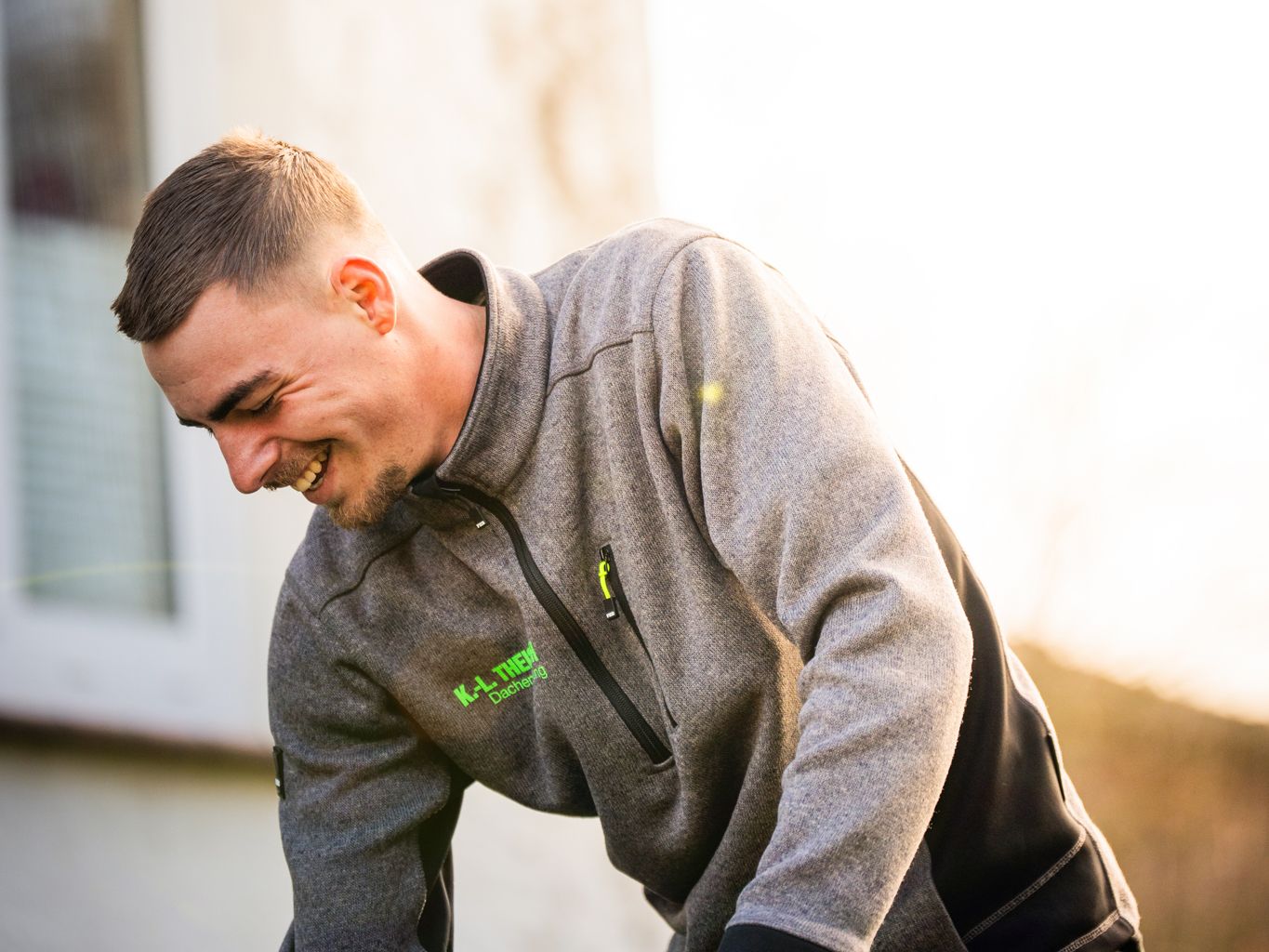 Mitarbeiter steht mit einem Gerät vor einer Hauswand