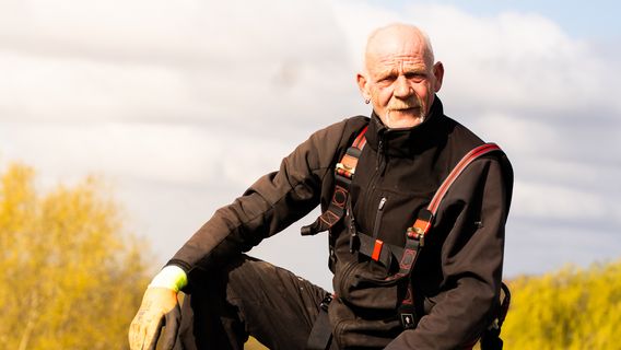 Ein Mitarbeiter sitzt auf einem Flachdach mit dem Himmel als Hintergrund