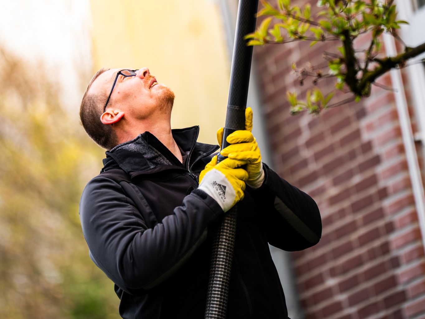 Ein Mitarbeiter hält ein Reinigungsrohr in die Höhe und blickt dabei nach oben