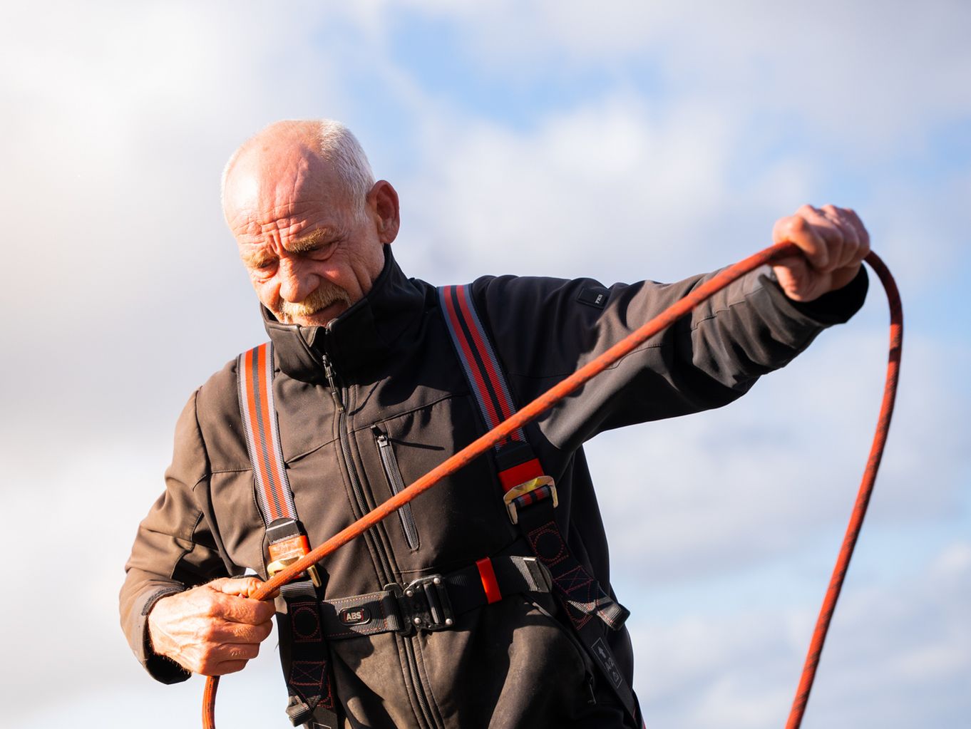 Ein Mitarbeiter steht mit einem Sicherungsseil auf einem Dach.