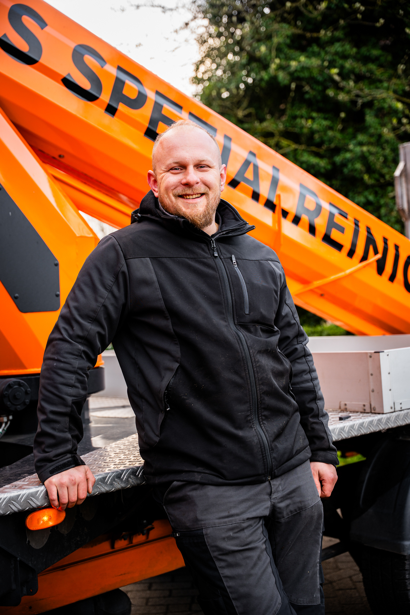 Mitarbeiter steht am Fahrzeug mit Hebebühne gelehnt