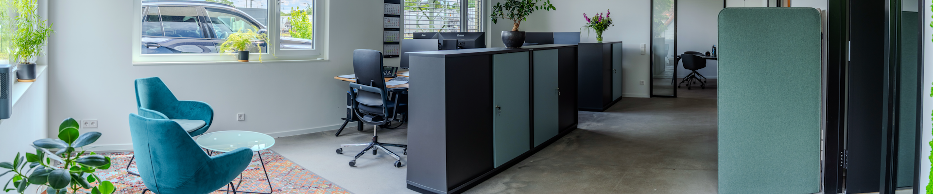 Büroraum mit Einrichtung in verscheidnenen Grautönen und Türkis